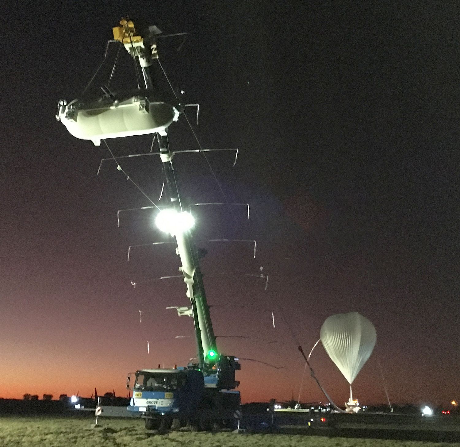 The launch vehicle hoisting the GRAINE instrument. Inthe background, the balloon still being inflated.